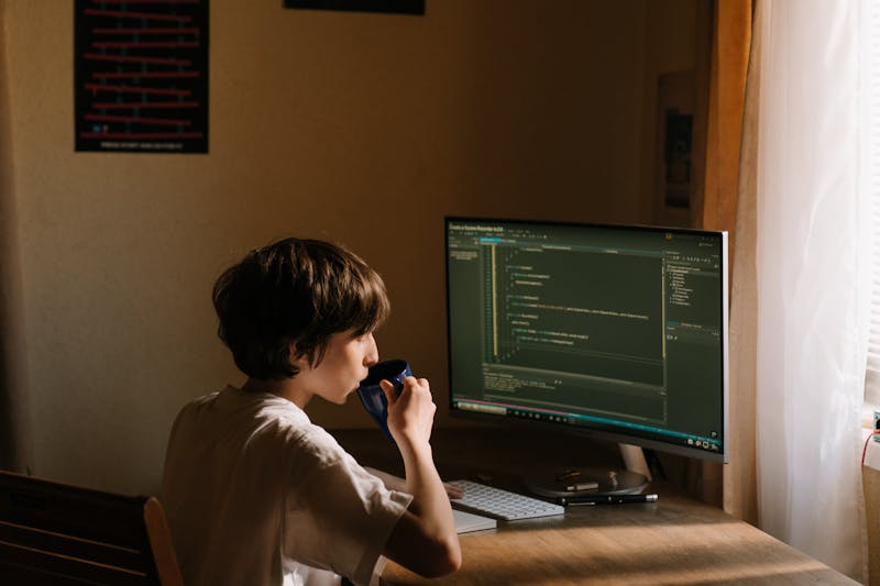 Teenager coding at a computer — active creation